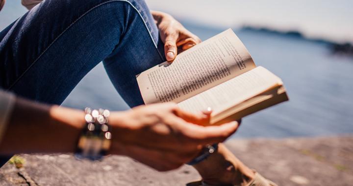 Mujer leyendo un libro cerca del mar